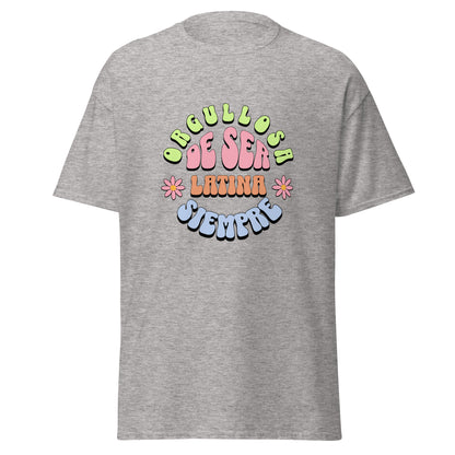 Retro groovy t-shirt design featuring "ORGULLOSA DE SER LATINA SIEMPRE" in curved bubble letters - lime green for "ORGULLOSA", soft pink for "DE SER", coral orange for "LATINA", and sky blue for "SIEMPRE", decorated with pink daisy flowers with yellow centers on both sides